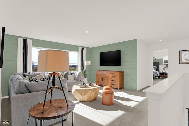 carpeted living room featuring wood walls