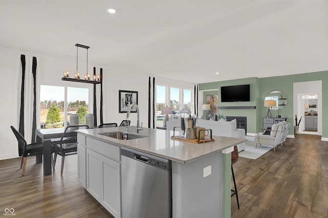 kitchen with an island with sink, sink, white cabinets, hanging light fixtures, and stainless steel dishwasher