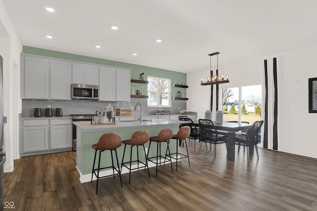 kitchen featuring decorative light fixtures, sink, a chandelier, a kitchen island with sink, and stainless steel appliances