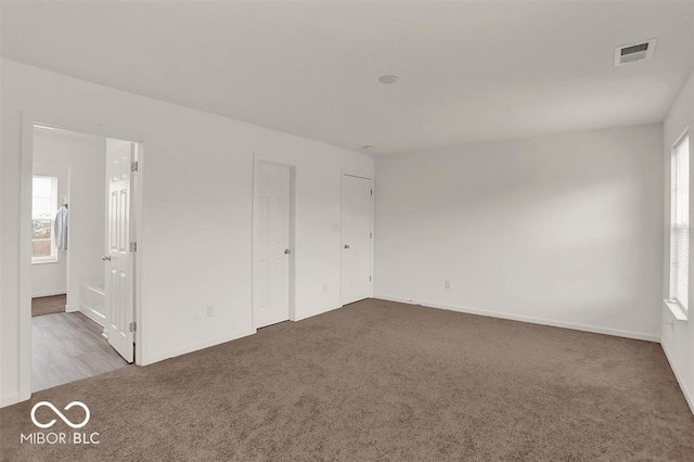 unfurnished bedroom with multiple windows and dark carpet