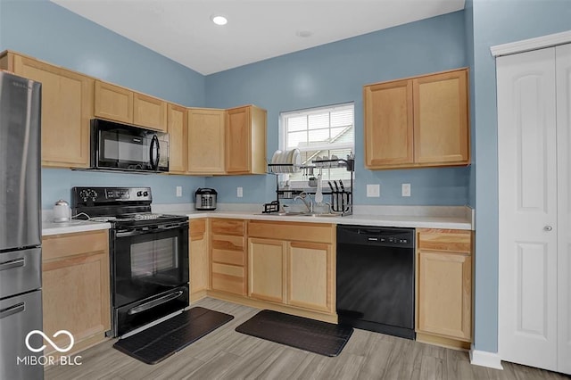 kitchen with black appliances, sink, light hardwood / wood-style floors, and light brown cabinets