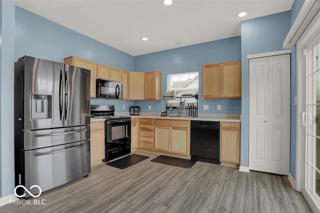 kitchen with black appliances, light wood-type flooring, light brown cabinetry, and sink