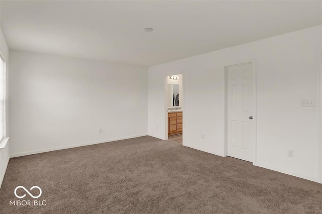 unfurnished bedroom with dark carpet and connected bathroom