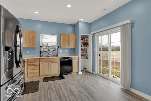 kitchen with light brown cabinetry, sink, black dishwasher, and stainless steel fridge with ice dispenser