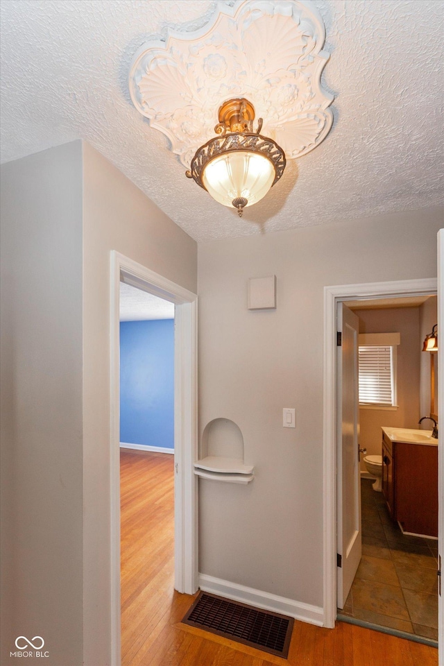 hallway featuring sink, a textured ceiling, and hardwood / wood-style floors