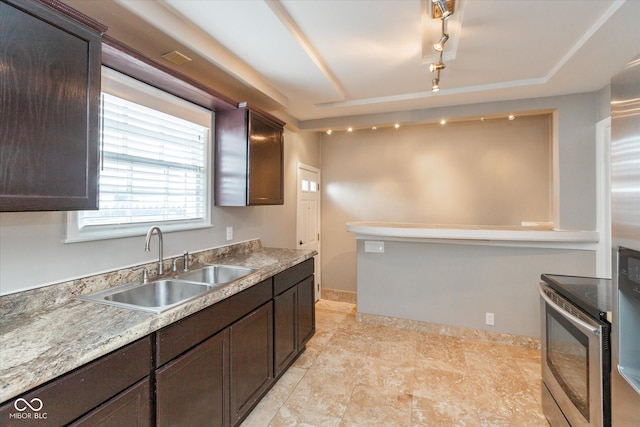 kitchen featuring stainless steel range with electric cooktop, sink, track lighting, and dark brown cabinetry