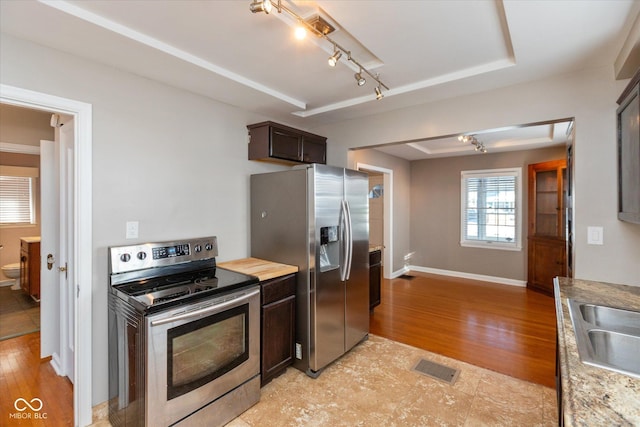 kitchen featuring dark brown cabinets, sink, stainless steel appliances, and light wood-type flooring