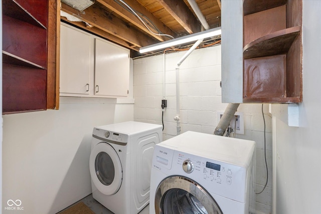 clothes washing area with washer and clothes dryer and cabinets