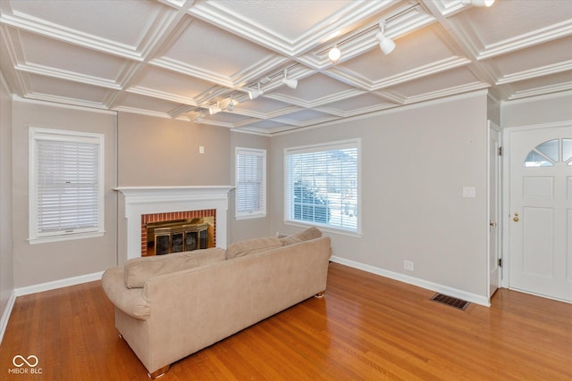 living room with a brick fireplace, hardwood / wood-style floors, and coffered ceiling