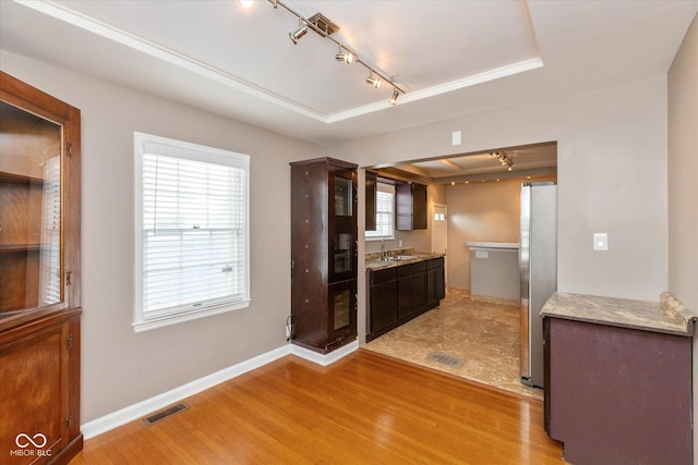 kitchen with stainless steel fridge, a healthy amount of sunlight, a raised ceiling, light hardwood / wood-style flooring, and sink