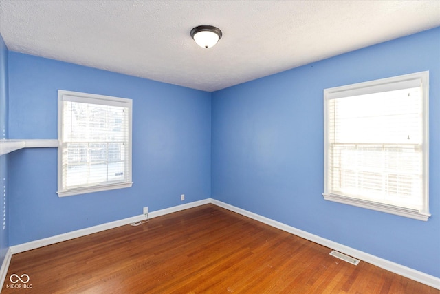 empty room featuring a textured ceiling and wood-type flooring