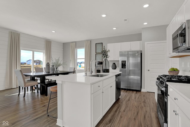 kitchen featuring appliances with stainless steel finishes, white cabinetry, sink, a kitchen island with sink, and dark wood-type flooring