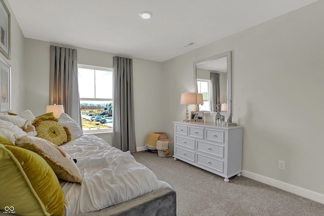 bedroom with multiple windows and light carpet