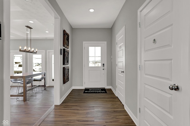 foyer entrance with dark hardwood / wood-style flooring, plenty of natural light, and a chandelier