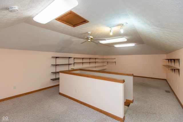 bonus room with vaulted ceiling, light carpet, and a textured ceiling