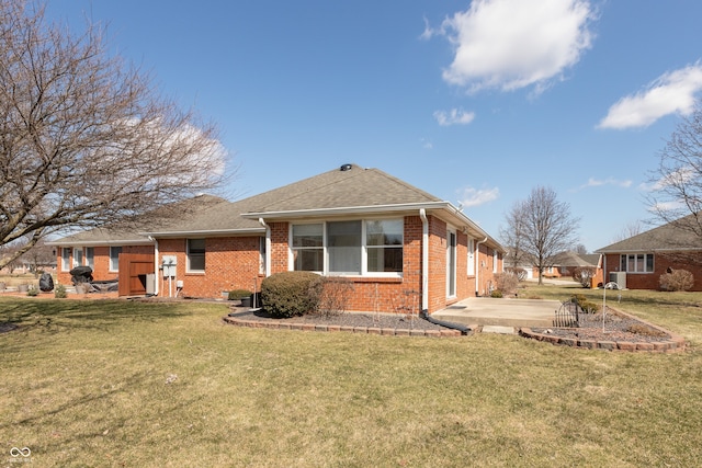 back of house with brick siding, a shingled roof, a yard, driveway, and a patio