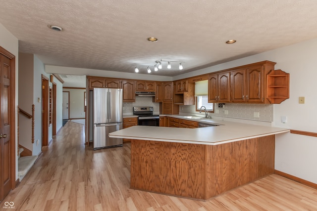 kitchen featuring open shelves, brown cabinets, a peninsula, stainless steel appliances, and a sink