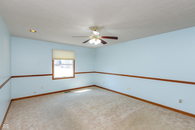 carpeted spare room featuring visible vents, a textured ceiling, baseboards, and a ceiling fan