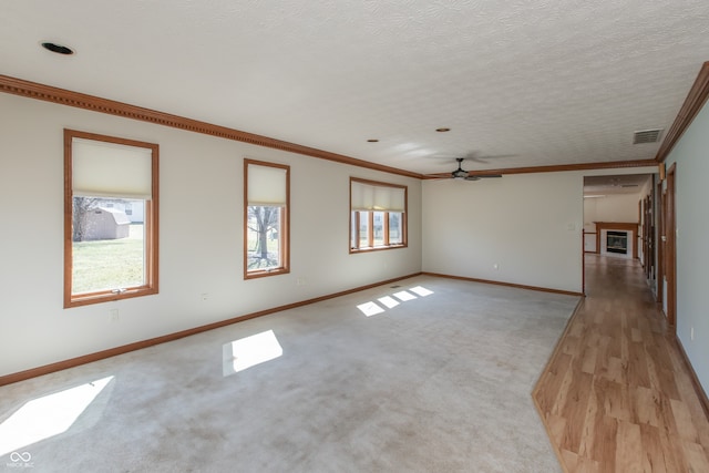 unfurnished room featuring visible vents, ornamental molding, a textured ceiling, a fireplace, and baseboards