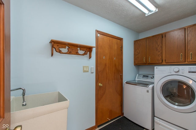 clothes washing area with washer and dryer, a textured ceiling, cabinet space, and a sink