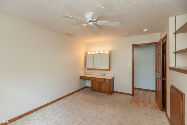 unfurnished bedroom with visible vents, baseboards, light colored carpet, and built in desk