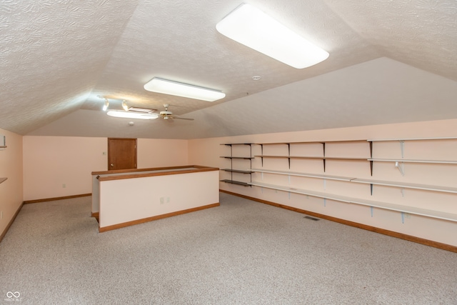 additional living space with light colored carpet, lofted ceiling, a textured ceiling, and baseboards