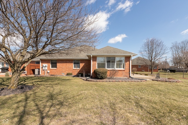 view of front of house featuring brick siding, roof with shingles, and a front yard