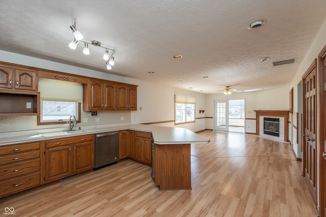 kitchen with dishwasher, a peninsula, light wood-style floors, and visible vents