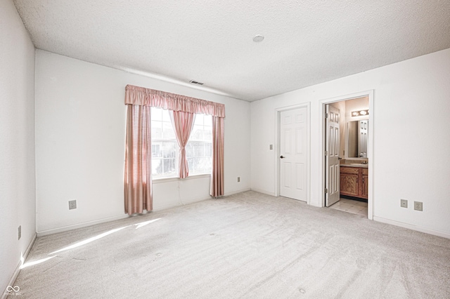 spare room featuring a textured ceiling and light carpet