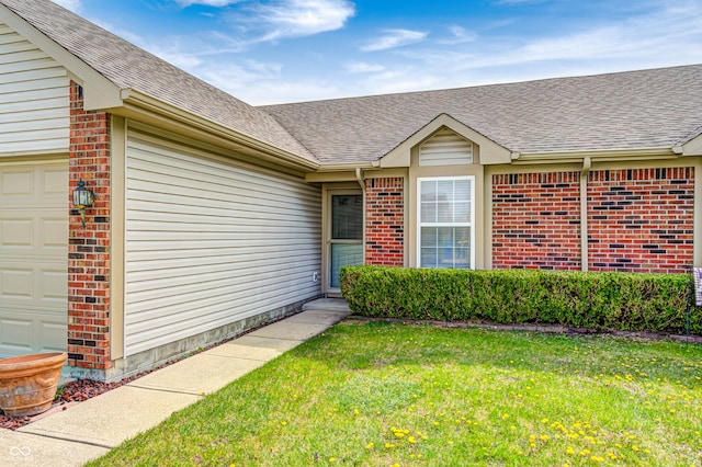 7259 Registry Dr, Indianapolis, IN 46217 - entrance to property featuring brick siding, roof with shingles, a yard, and a garage