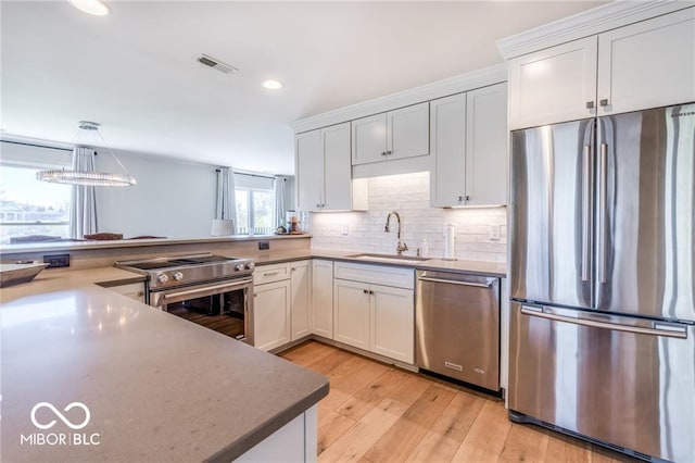 kitchen featuring stainless steel appliances, white cabinetry, hanging light fixtures, and sink