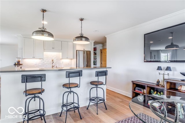 kitchen featuring white cabinetry, stainless steel fridge, a kitchen breakfast bar, and kitchen peninsula