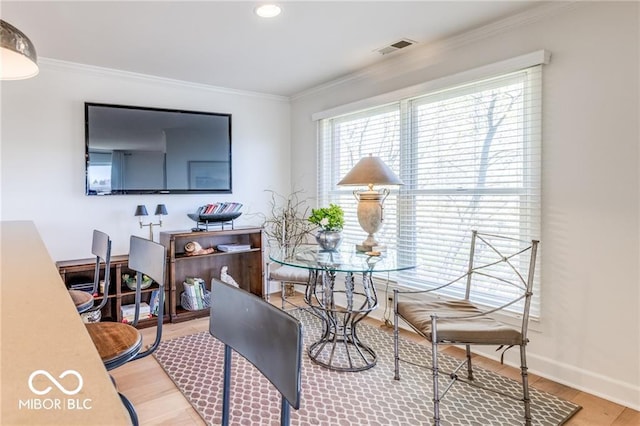 dining area with crown molding and light hardwood / wood-style floors