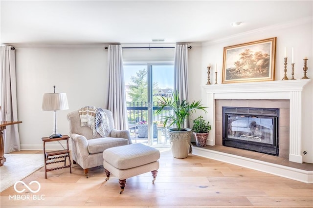 living area featuring a fireplace, crown molding, and light hardwood / wood-style flooring