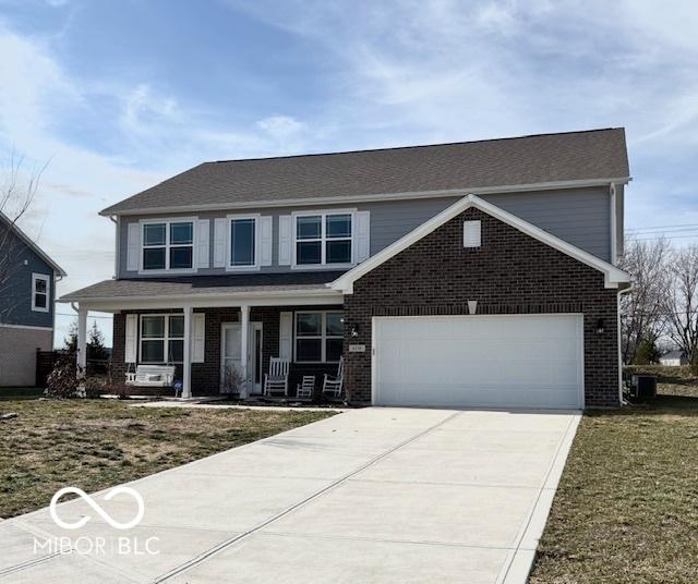 view of property with a garage, a porch, and a front lawn