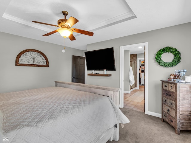 bedroom with ceiling fan, light colored carpet, and a tray ceiling