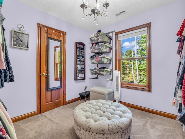 sitting room with a textured ceiling, an inviting chandelier, and carpet floors