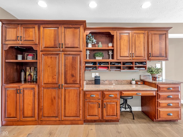 kitchen featuring light hardwood / wood-style floors, light stone counters, and built in desk