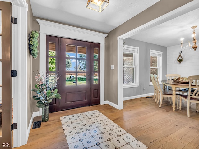 entrance foyer with light hardwood / wood-style floors, a textured ceiling, and a notable chandelier