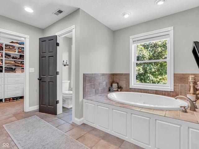 bathroom with toilet, a bathtub, and tile patterned floors