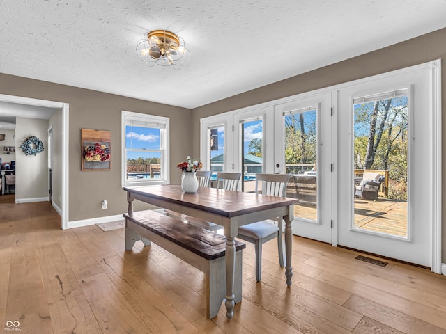 dining area with french doors, a textured ceiling, and light hardwood / wood-style flooring