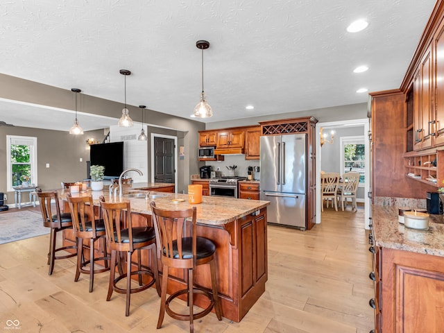 kitchen featuring decorative light fixtures, light stone countertops, a large island, and stainless steel appliances