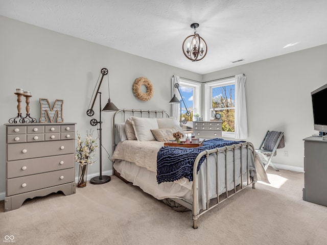 bedroom featuring a textured ceiling, light carpet, and an inviting chandelier