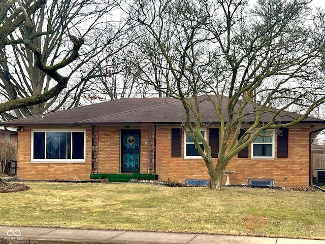 ranch-style house with a front lawn, roof with shingles, cooling unit, and brick siding