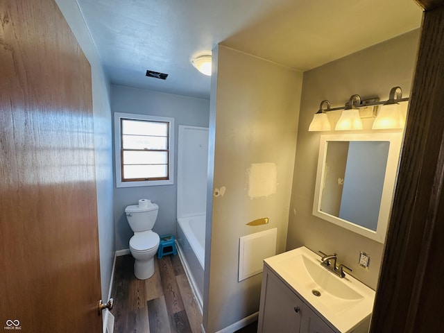 bathroom with toilet, a tub, wood-type flooring, and vanity