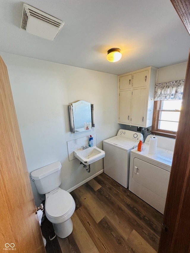 bathroom featuring separate washer and dryer, wood-type flooring, toilet, and sink