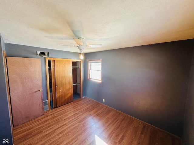 unfurnished bedroom with ceiling fan, hardwood / wood-style floors, and a closet