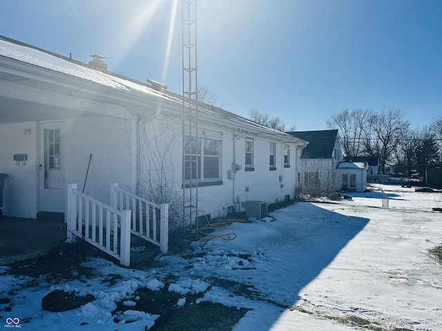 view of snow covered exterior featuring cooling unit