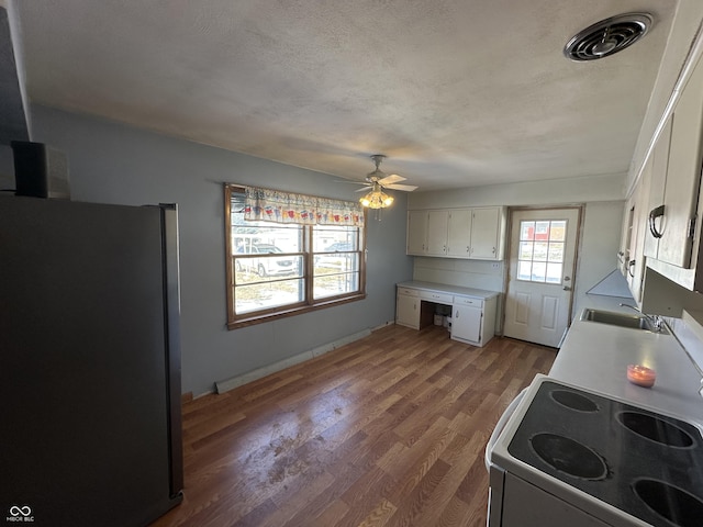 kitchen featuring wood-type flooring, stainless steel refrigerator, sink, white electric range oven, and white cabinets