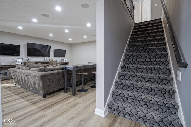 staircase featuring a textured ceiling and hardwood / wood-style floors